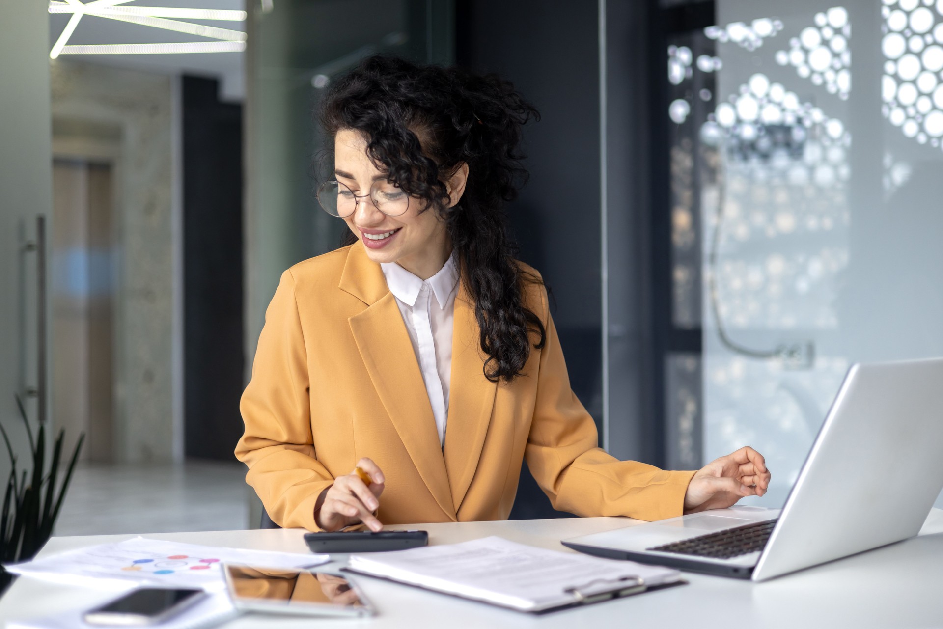 Mature successful financier accountant on paper work with papers, documents contracts and charts graphs, businesswoman boss with calculator smiling happy with achievement results, inside office